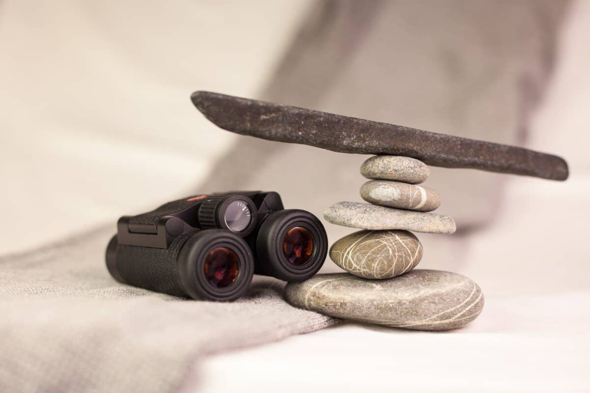 black binoculars on white textile near stones