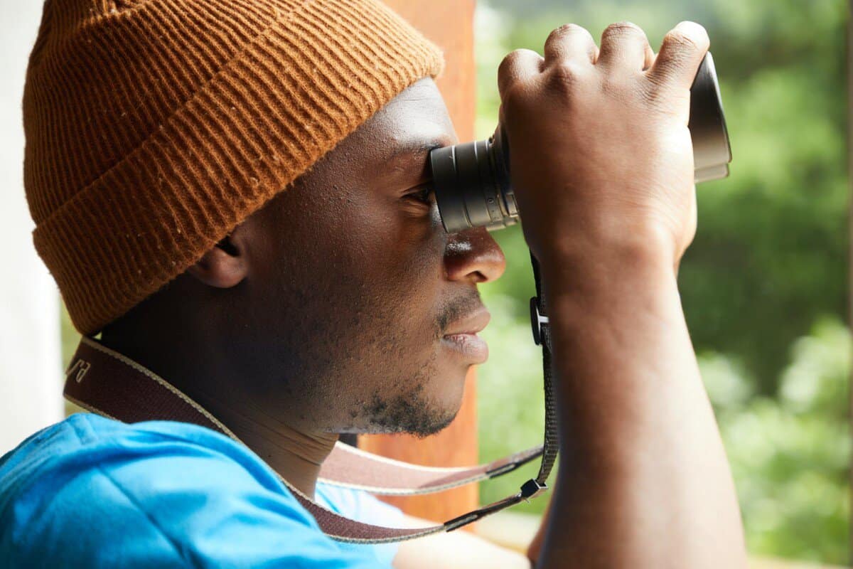 african american man with binoculars on balcony