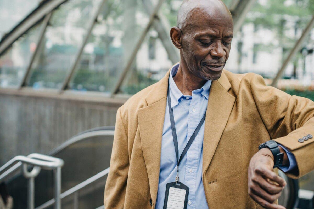 crop black man checking time on wristwatch near metro station